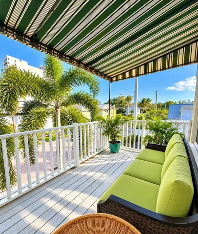 Covered balcony featuring white railing, light-toned wood-finish flooring, and a retractable striped awning