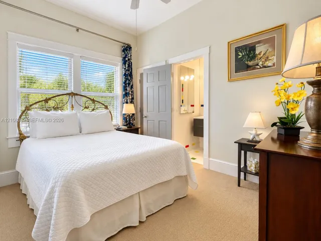 Bedroom featuring neutral wall color, plush carpeting, high ceilings with a mounted fan, and large windows with multi-pane glass