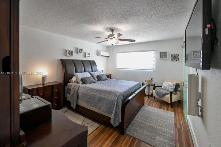 Room featuring wood-finish flooring, a wall-mounted ductless air conditioning unit, a ceiling fan with integrated lighting, and a window with horizontal​​‌​​​​‌​​‌‌​‌‌​​​‌‌​‌​‌​‌​​​‌​​ blinds