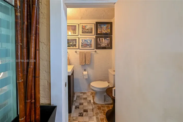Restroom featuring a wall-mounted metal towel bar, dark-finish cabinetry, and square multi-tone tile flooring