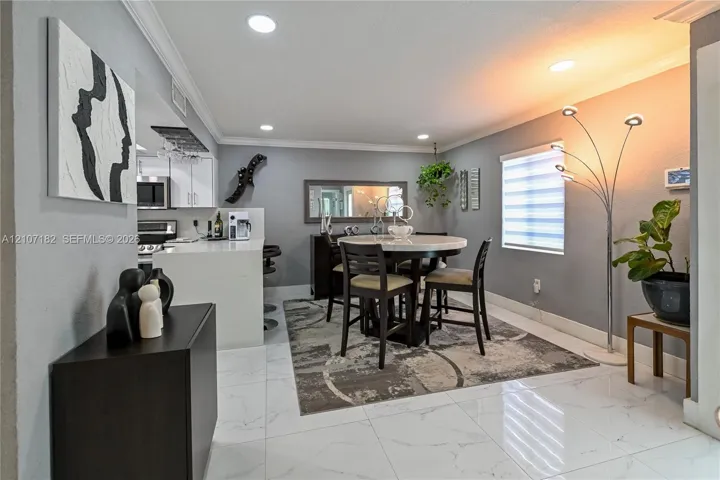 Large-format tile flooring, recessed lighting, crown molding, and a kitchen island with a light-toned countertop