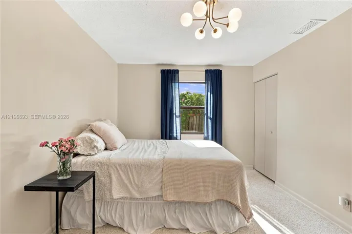 Neutral-toned walls, multi-arm light fixture with frosted glass globes, carpeted flooring, and reach-in closet with double doors