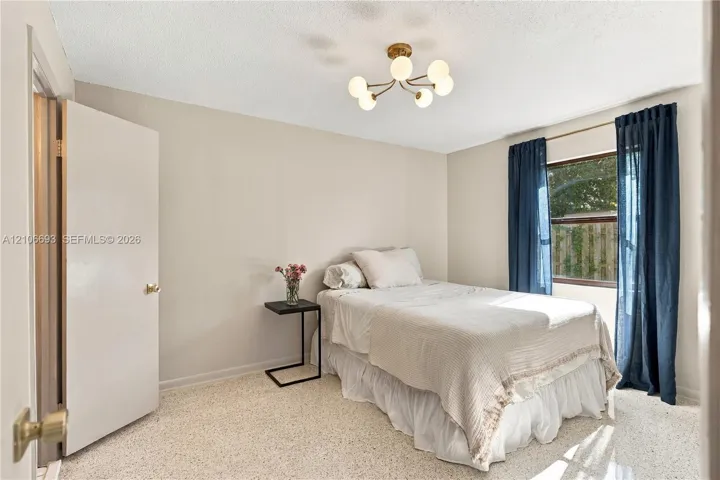 Neutral wall palette with terrazzo flooring, six-light globe-style chandelier, and a wide-set window
