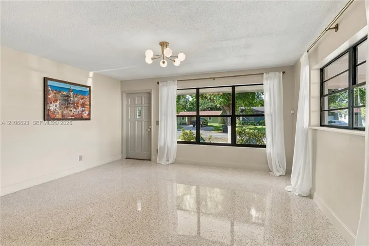 Polished terrazzo flooring, expansive multi-pane windows with black frames, modern multi-globe flush-mount lighting, and a neutral color palette