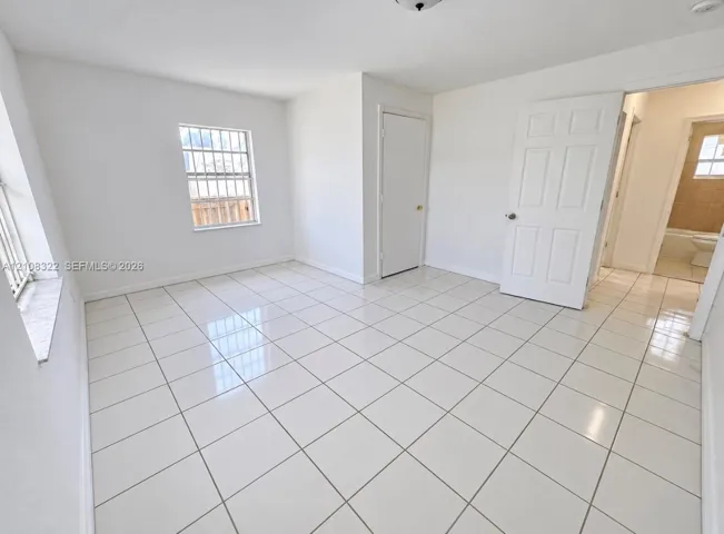 Neutral-toned interior space featuring polished tile flooring, white-painted walls, and six-panel interior doors