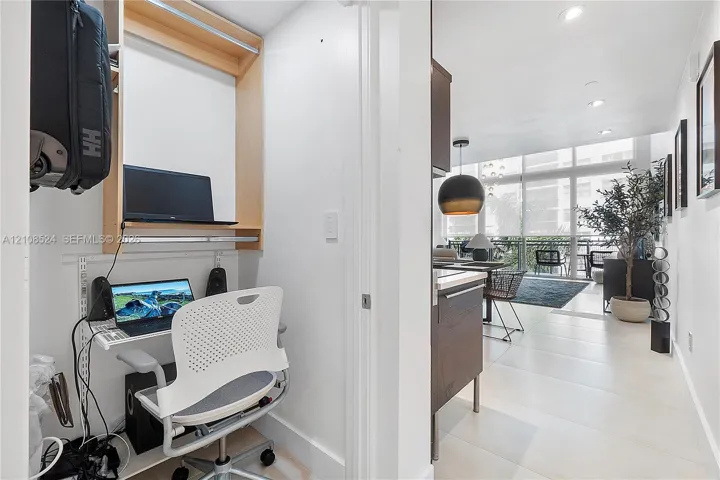Built-in workstation featuring wood-finish shelving, large-format tile flooring, floor-to-ceiling glass wall panels, recessed lighting, and a pendant light fixture