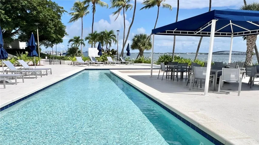 Rectangular lap pool featuring light-toned stone decking and a covered pavilion structure