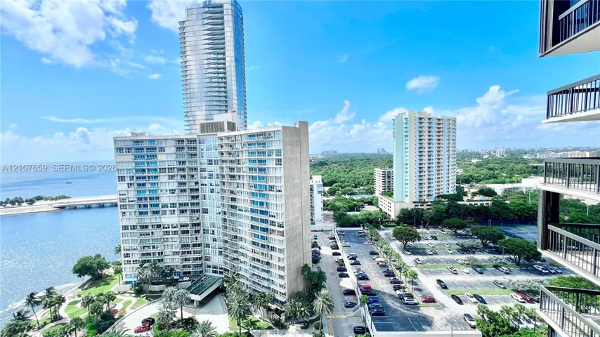 High-rise exterior balcony with metal railing, showcasing coastal scenery and urban skyline
