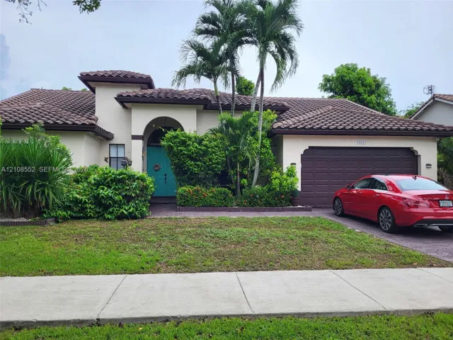 Stucco exterior featuring a multi-gabled clay tile roof, arched entryway, and attached multi-car garage
