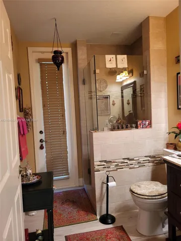Glass-enclosed shower with floor-to-ceiling tile, decorative stone accent border, and wood-finish flooring