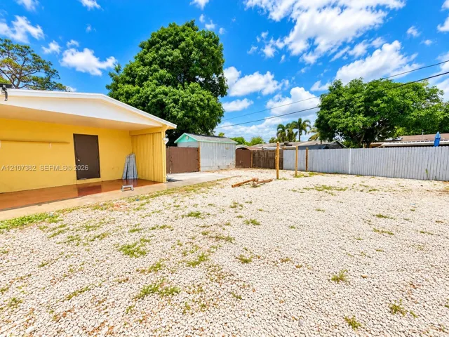 Exterior area featuring a covered patio, gravel ground cover, detached storage shed, and perimeter fencing