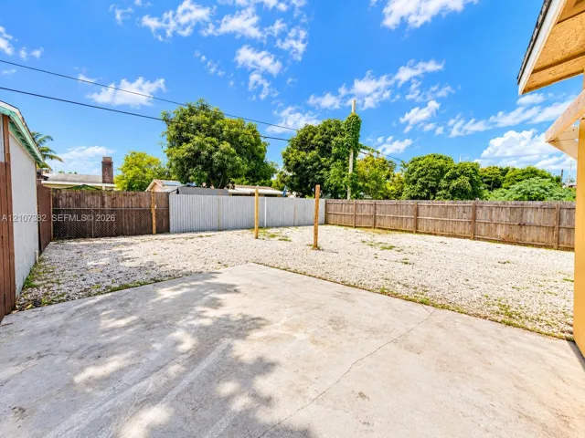 Backyard featuring a concrete patio, gravel ground cover, and full wood perimeter fencing