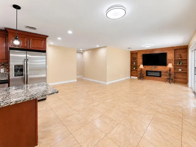 Kitchen featuring stone-surface countertops, dark wood cabinetry, and stainless steel refrigerator