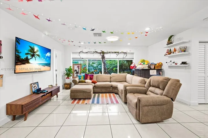 Living area featuring large-format tile flooring, recessed lighting, and built-in wall shelving