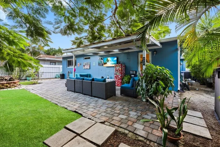 Backyard featuring a paved stone patio, a covered pergola, a manicured lawn, and a circular brick fire pit