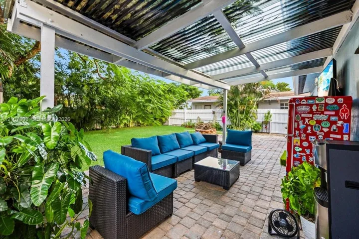 Covered patio featuring a corrugated translucent roof, paver flooring, and white privacy fencing