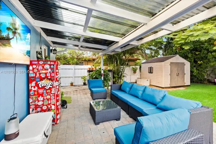 Covered patio featuring a translucent roof, stone-paver flooring, and a fenced backyard with a storage structure