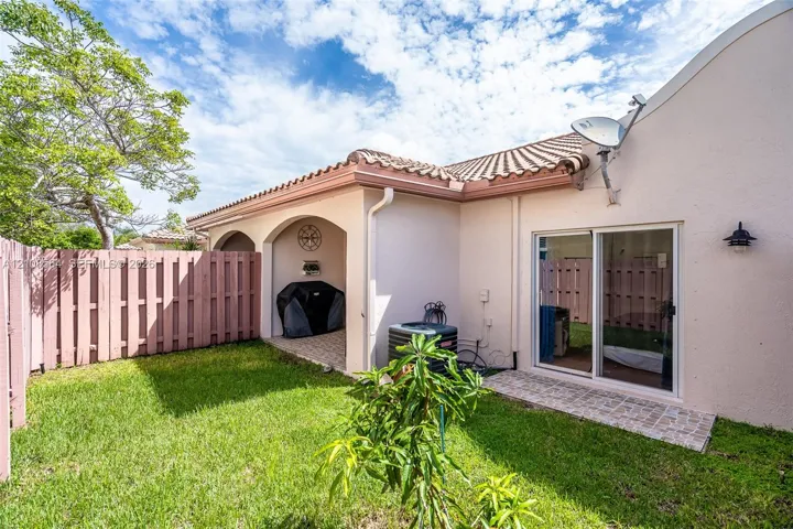 Private backyard featuring a covered patio, paved stone hardscaping, and privacy fencing