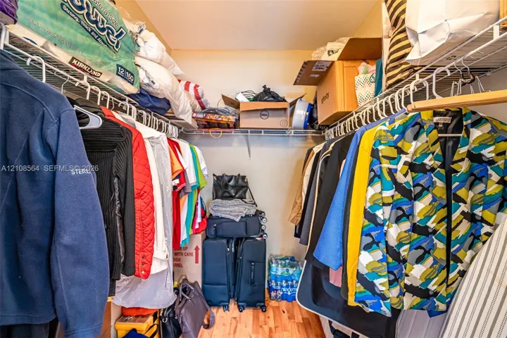 Reach-in closet featuring multi-level wire shelving and wood-finish flooring