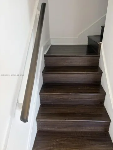 Staircase featuring dark-toned wood-finish treads and a coordinating round handrail