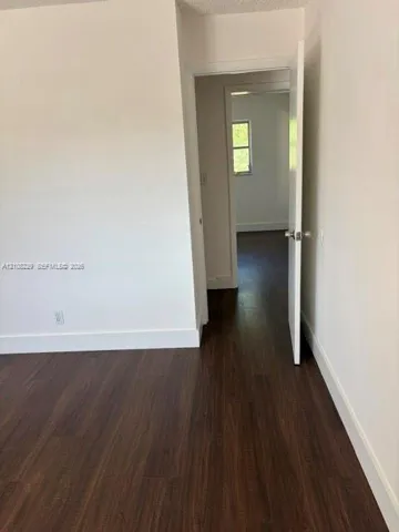 Interior room featuring white-painted walls and dark wood-finish flooring