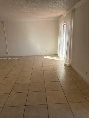 Room featuring neutral-toned tile flooring, textured ceiling finish, and a sliding glass door