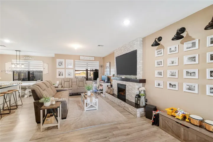 Floor-to-ceiling stone-faced fireplace with a wood mantel and built-in hearth, wood-finish flooring, recessed lighting, and wall-mounted industrial-style light fixtures