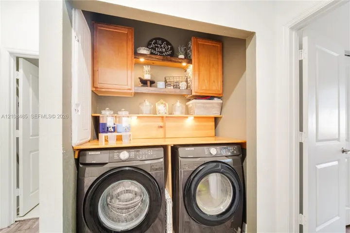 Laundry area featuring built-in wood cabinetry, integrated under-cabinet lighting, natural wood shelving, and a custom wood countertop
