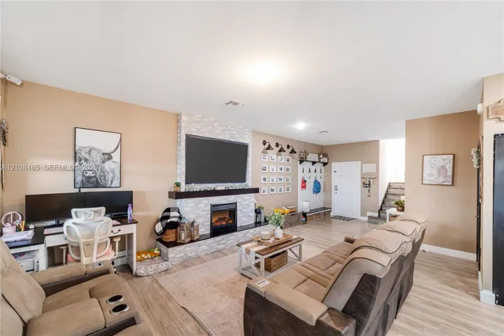 Living area featuring stone-clad fireplace, dark wood mantel, recessed lighting, and wood-finish flooring
