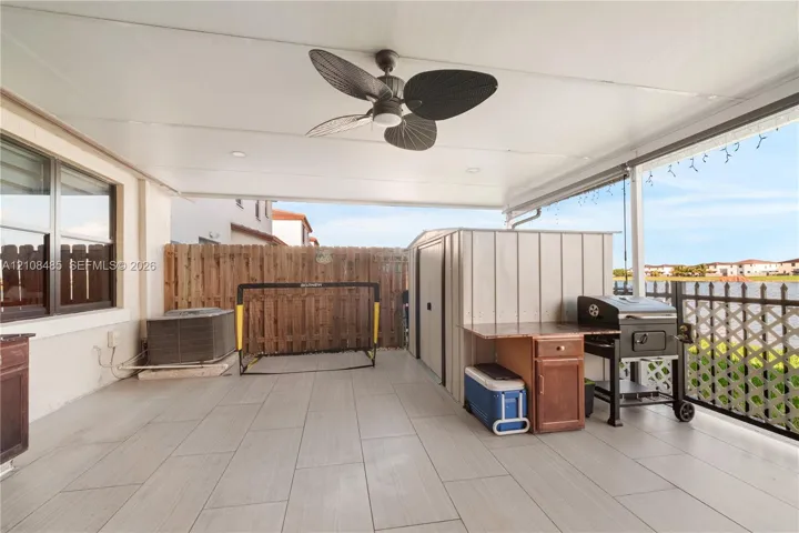 Covered patio featuring ceramic tile flooring, a ceiling fan, and metal lattice screening