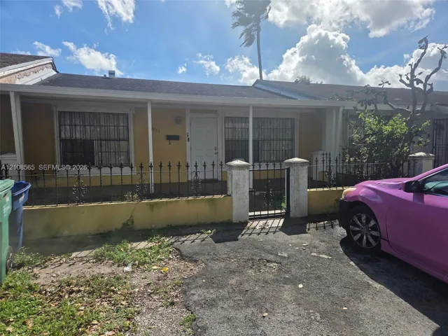 Single-story residence featuring a covered front porch, stucco exterior, decorative metal fencing with concrete pillars, and metal window security bars