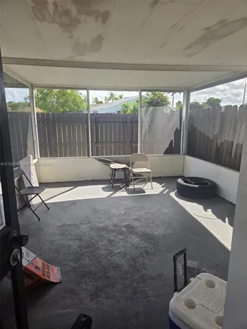 Enclosed porch featuring a concrete floor, screened-in walls, a solid roof, and a wooden privacy fence