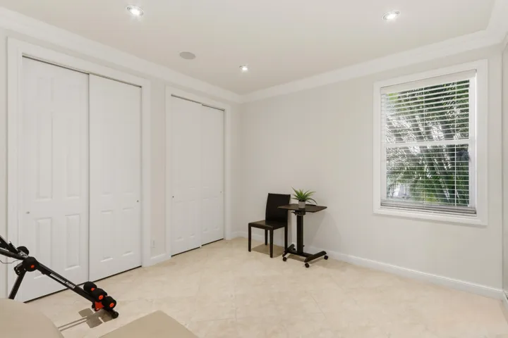 Neutral-toned tile flooring, recessed ceiling lighting, crown molding, and two sets of double-panel closet doors