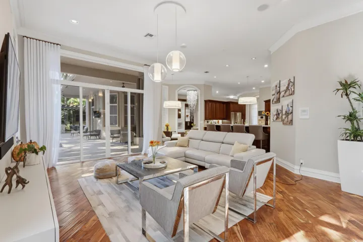 Open-concept living space featuring wood-finish flooring, recessed lighting, multi-pendant light fixtures, and expansive glass sliding doors