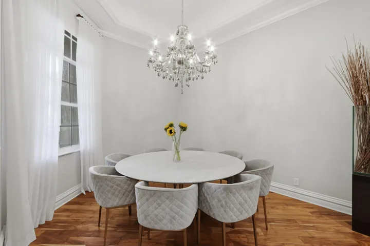 Tray ceiling featuring a crystal chandelier and wood-finish flooring