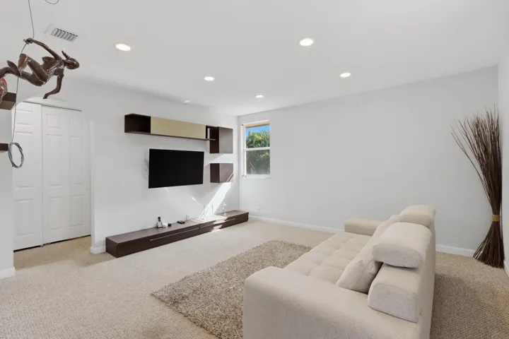 Recessed ceiling lighting, wall-mounted cabinetry, custom media shelving, and dual-panel closet doors