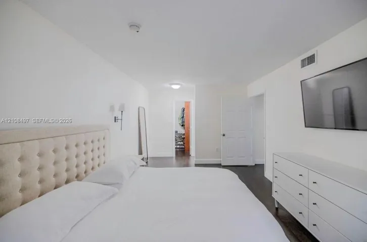 Neutral color palette featuring dark wood-finish flooring, white walls, flush-mount ceiling lighting, and wall-mounted sconce fixtures