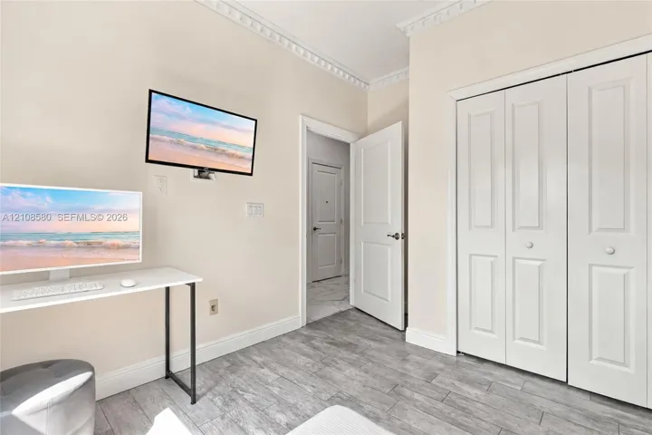 Wood-finish plank flooring, decorative crown molding, two-panel interior doors, and double-panel bifold closet doors