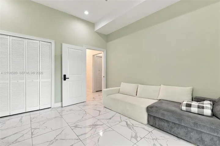 Interior space featuring white stone-finish tile flooring, louvered closet doors, and a recessed ceiling light