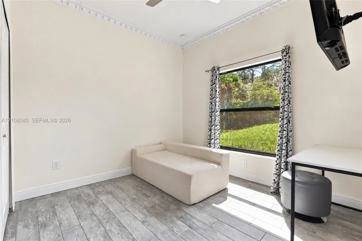 Room featuring wood-finish tile flooring, decorative crown molding, and a large window