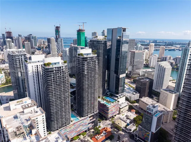 High-rise urban landscape featuring contemporary skyscrapers, glass-facade architecture, rooftop outdoor swimming pools, and proximity to coastal waters