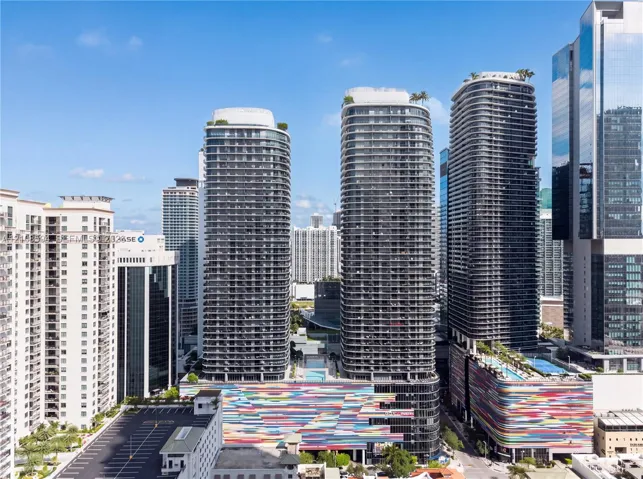High-rise glass facade residential towers featuring expansive balconies, roof-level outdoor recreation decks, and a colorful multi-story architectural podium