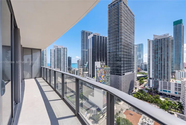 Covered balcony featuring concrete flooring and a glass-paneled railing