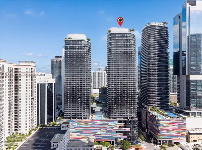 High-rise tower featuring a glass facade, multiple balconies, a rooftop terrace, and architectural detailing with a multi-colored exterior finish