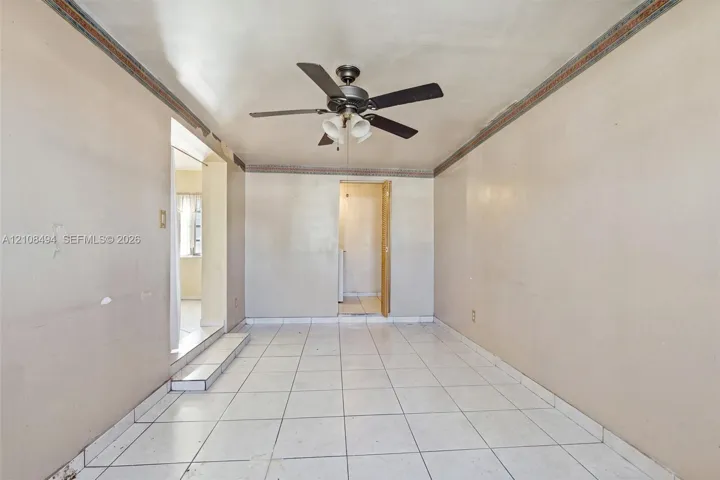 Interior space featuring white tile flooring, ceiling fan with integrated lighting, and decorative crown molding