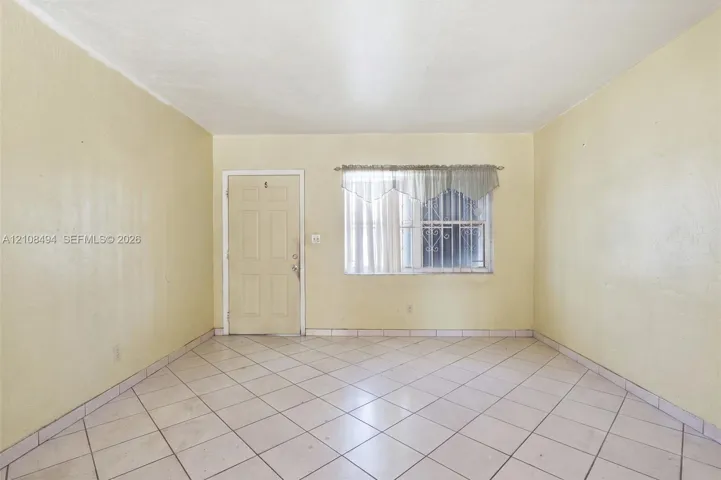 Interior space featuring diagonal ceramic tile flooring, a six-panel exterior entry door, and a window with security bars
