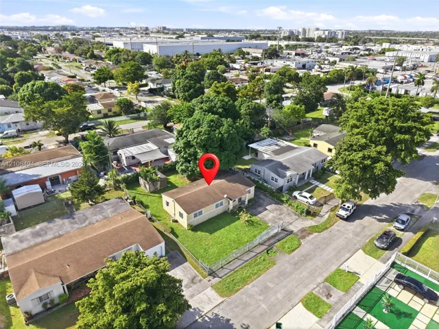 Aerial perspective of a single-story residence featuring a shingled roof, exterior siding, and a front lawn enclosed by perimeter fencing