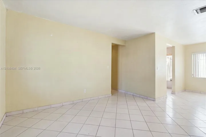 Interior space featuring neutral-toned walls, tile flooring set on a diagonal pattern, and vertical slat window blinds
