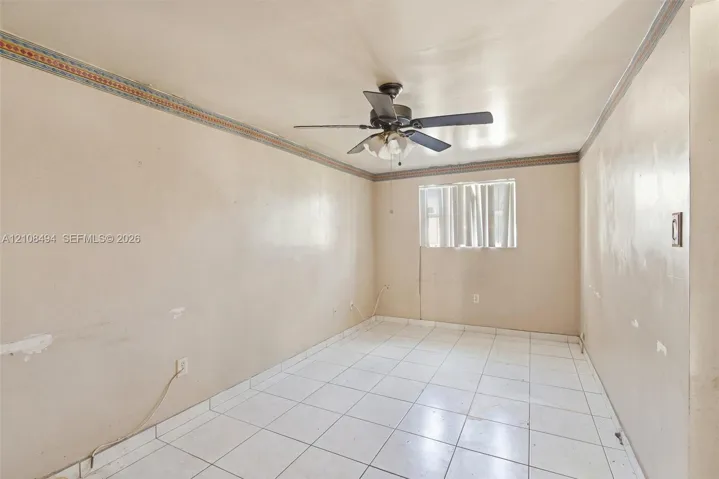 Interior room featuring light-toned tile flooring, decorative crown molding, and a central ceiling fan with an integrated light fixture