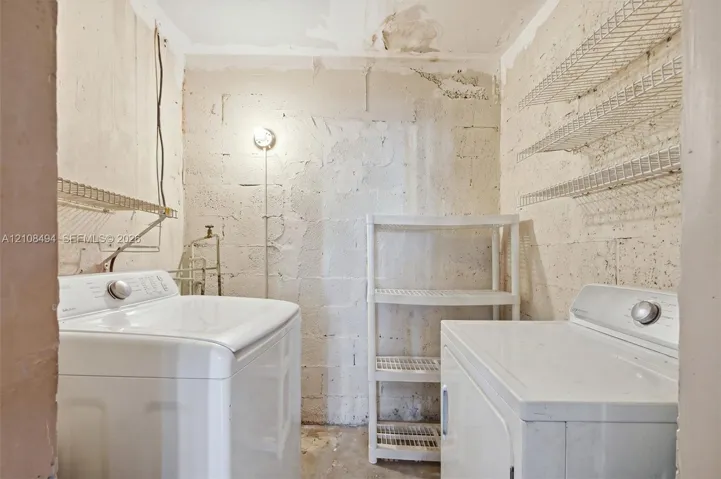 Utility area featuring concrete masonry unit walls, wire shelving, and exposed plumbing connections